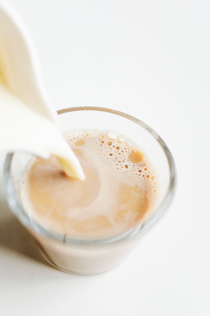 A close-up of milk being poured into a freshly brewed cup of coffee, creating a smooth blend.